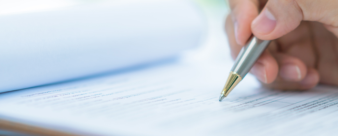 Closeup of hand with pen writing on paper form