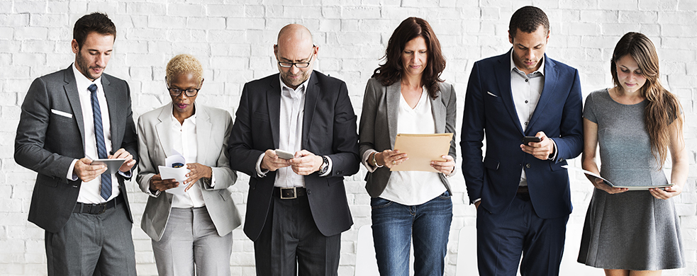 Group of diverse businesspeople reading on their devices or paperwork